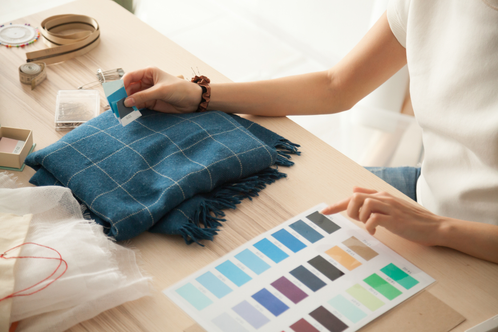 A woman checks a piece of fabric against a color swatch